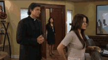 a man in a priest collar stands next to two women