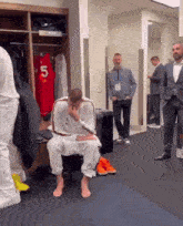 a man sitting in a locker room with a jersey that says 5