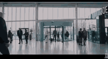 a group of people are walking in a large room with a sign that says que