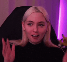 a woman with blonde hair is sitting in a chair and making a surprised face .