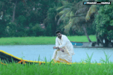 a man standing in a field next to a body of water with the name pranay_varma on the bottom