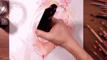 a person is holding a black object in their hand and drawing on a piece of paper