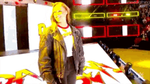 a woman is standing on a stage wearing a leather jacket and a white shirt .