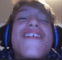 a close up of a person 's face with headphones on making a funny face .