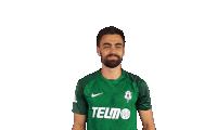 a man wearing a green telmo shirt wipes his forehead
