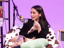 a woman sitting in a chair with a stuffed animal and a microphone behind her