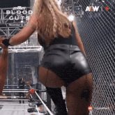 a woman in leather shorts is standing in front of a fence .