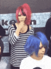 a woman with red hair and a man with blue hair are standing next to each other .