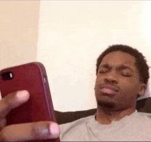 a man is making a funny face while looking at his phone .