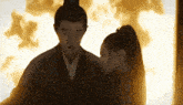 a man and a woman standing next to each other in front of a fire
