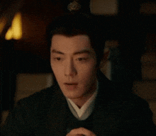 a man in a black jacket is holding a chess piece in his hand .