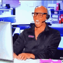 a man wearing glasses and a headset is sitting in front of a computer .