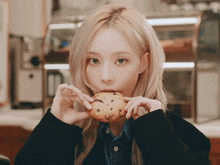a woman with blonde hair is eating a cookie