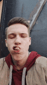 a young man with his eyes closed and a piece of meat in his mouth