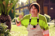 a woman wearing a green striped sweater and overalls with the word hagore on them