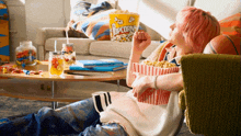 a person eating popcorn in front of a bucket that says popcorn on it