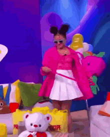 a woman in a pink coat and white skirt is holding a pink teddy bear