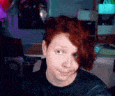 a woman with red hair is wearing a black shirt and making a face