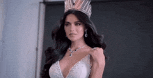 a woman wearing a crown and a necklace is standing in front of a door .