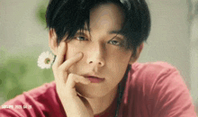 a close up of a young man 's face with a flower in his ear .