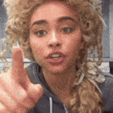 a woman wearing a wig is pointing her finger at the camera .