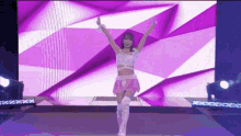 a woman is standing on a stage with her arms in the air in front of a large screen .