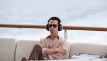a man wearing headphones and sunglasses is sitting on a couch on a boat .