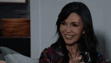 a woman is sitting on a couch holding a glass of wine and smiling