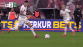 a soccer player kicks a ball in front of a sign that says " ts "