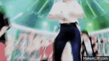 a man in a white shirt and blue pants is dancing on a stage .
