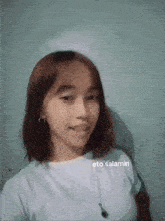 a young girl is taking a selfie with a necklace around her neck and a white shirt .