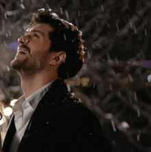 a man in a suit and tie is laughing in the rain
