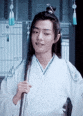 a man in a white kimono is holding a sword and smiling .