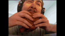 a man wearing headphones is holding a hamburger in his hands