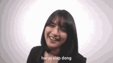 a woman is smiling with the words harus siap dong above her