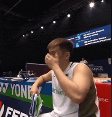 a man sits in front of a yonex advertisement