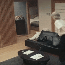 a woman is standing in a living room next to a black couch .
