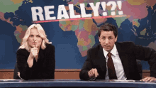 a man and a woman sitting at a desk with a sign that says really