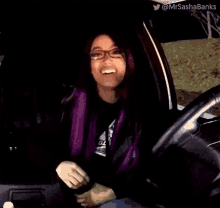 a woman with purple hair and glasses is sitting in a car asking what 's going on ..