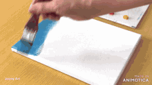 a person is painting on a canvas with the words made in animatica on the bottom right