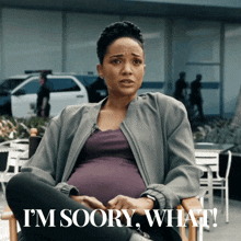 a pregnant woman is sitting in a chair with the words i 'm soory what
