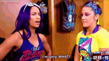 two women are standing next to each other in a room and talking .