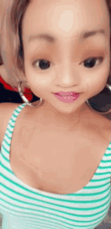 a woman wearing a striped tank top and hoop earrings is taking a selfie