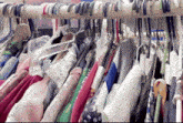 a bunch of clothes are hanging on a rack and one of them has a blue ribbon around it