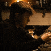 a man in a black sweater is sitting at a table with a spoon in his hand