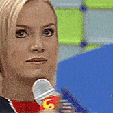 a close up of a woman holding a microphone with the number 6 on it
