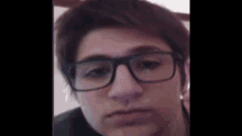 a young man wearing glasses is making a face .