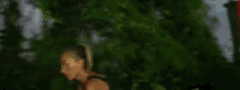 a woman in a blue tank top is running in the woods .