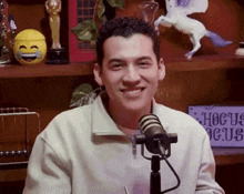a man sitting in front of a microphone with a sign that says hocus pocus on it