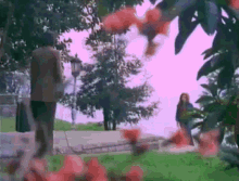 a man and a woman are walking in a park with trees in the background